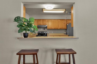 Kitchen featuring freestanding refrigerator, light countertops, stainless steel electric range oven, under cabinet range hood, and a breakfast bar