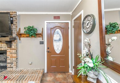 Tiled foyer with crown molding and a fireplace