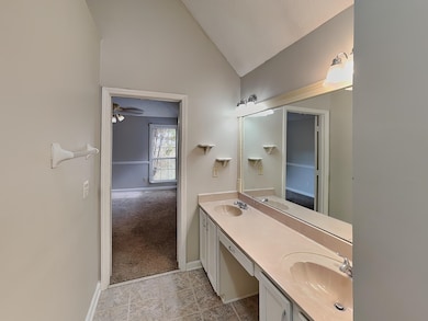 Bathroom with double vanity, lofted ceiling, ceiling fan, and light carpet