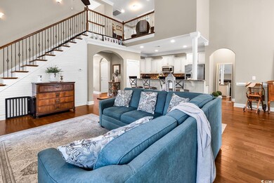 Living area featuring arched walkways, a high ceiling, dark wood-style flooring, and baseboards