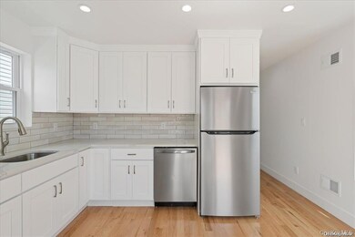 Kitchen featuring stainless steel appliances, white cabinets, light stone countertops, light wood-type flooring, and recessed lighting