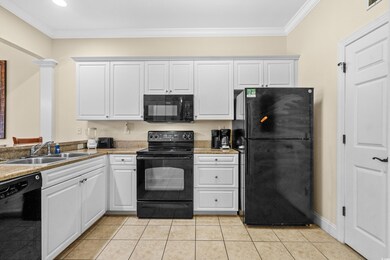 Kitchen with black appliances, light tile patterne