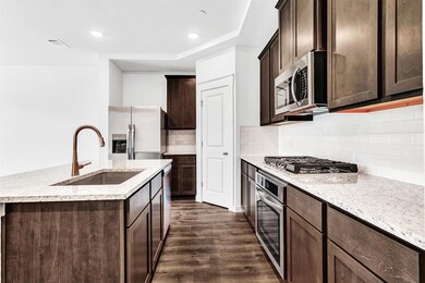 Kitchen with appliances with stainless steel finishes, sink, dark hardwood / wood-style floors, and tasteful backsplash