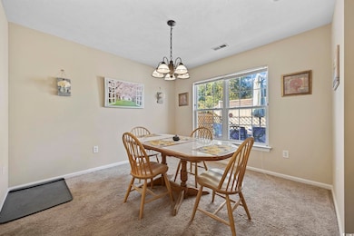 Dining space with light colored carpet, a chandelier, and a textured ceiling