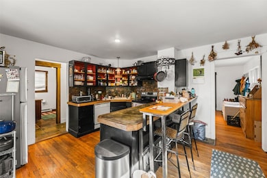 Kitchen with dark cabinetry, stainless steel appliances, a breakfast bar, and decorative backsplash