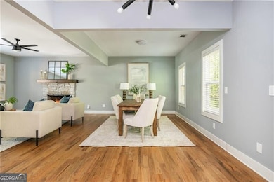 Dining room featuring ceiling fan, a fireplace, wood finished floors, and baseboards