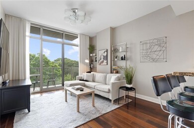 Living room with healthy amount of natural light, wood finished floors, expansive windows, and a chandelier