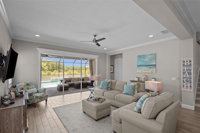Living Room with crown molding and views of pool and conservation