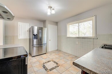Kitchen featuring tile walls, black electric range, stainless steel fridge, extractor fan,