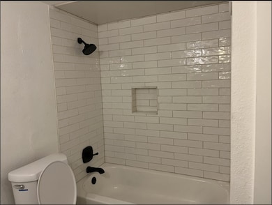 Bathroom featuring washtub / shower combination and toilet