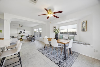 Dining room with arched walkways, a ceiling fan, and light tile patterned flooring