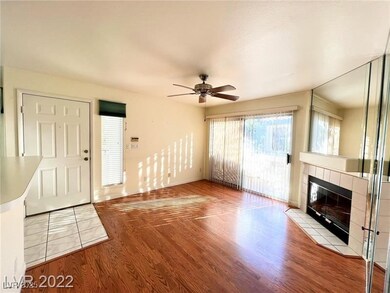 Living room with cozy gas fireplace , mirrored wall, upgraded laminate flooring, and a ceiling fan.