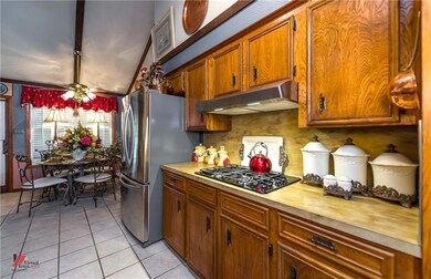 The kitchen features stained cabinets, gas cook to