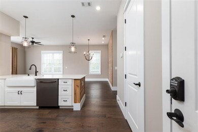 Kitchen featuring white cabinets, stainless steel dishwasher, decorative light fixtures, dark wood finished floors, and a ceiling fan