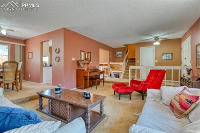 Living area featuring light carpet, stairway, a textured ceiling, and a ceiling fan