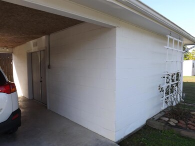 A large storage area with double doors for equipment opens from the carport.