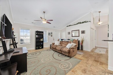 Living room with crown molding, ceiling fan, and l