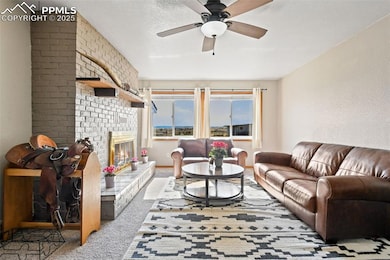 Carpeted living room with a brick fireplace and a ceiling fan