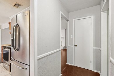 Hall with a textured ceiling and hardwood / wood-s