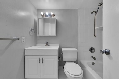Bathroom offers a tub/shower combo and white vanit