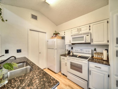 Kitchen with lofted ceiling, sink, light hardwood 