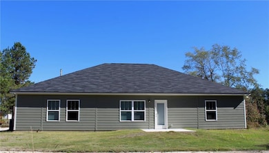 Rear view of house featuring a patio area, a lawn, and a shingled roof