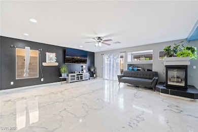 Living area with a glass covered fireplace, a ceiling fan, and recessed lighting