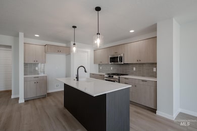 Kitchen featuring light brown cabinetry, decorative light fixtures, light wood-style floors, tasteful backsplash, and recessed lighting