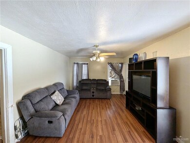 Living room with dark hardwood / wood-style flooring, a textured ceiling, and ceiling fan