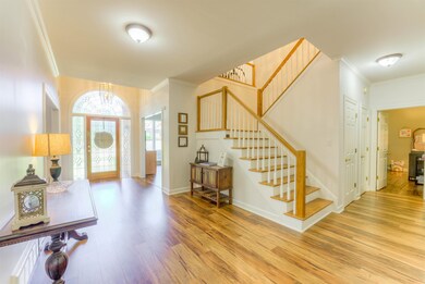 Foyer entrance featuring crown molding, light wood finished floors, stairway, and a chandelier