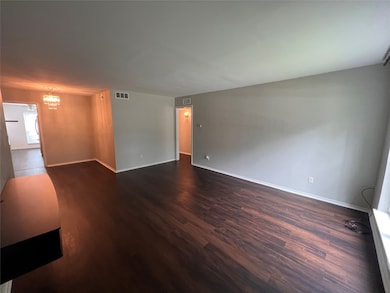 Livingroom featuring dark wood-style flooring and a chandelier