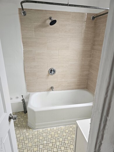 Bathroom with bathtub / shower combination and light tile patterned floors