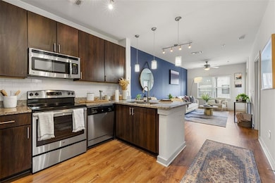 Kitchen with stainless steel appliances, sink, kitchen peninsula, light wood-type flooring, and decorative backsplash