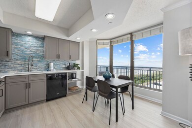 Kitchen featuring black dishwasher, sink, light wood-type flooring, decorative backsplash, and a water view
