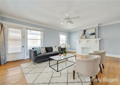 Living area with ornamental molding, a fireplace, light wood-style flooring, and ceiling fan