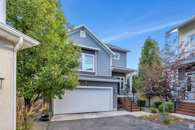 View of front of house with an attached garage, asphalt driveway, stairway, and roof with shingles