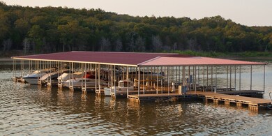 Dock featuring a water view, a view of trees, and boat lift