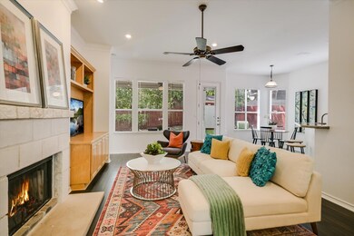 Living area featuring dark wood-type flooring, healthy amount of natural light, a fireplace, a ceiling fan, and crown molding