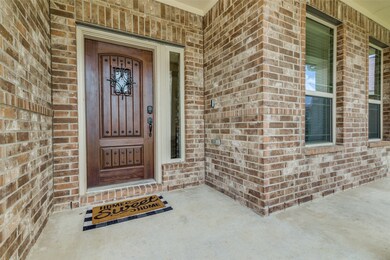 A close up of the front of the home and front porch.  Beautiful wood front door with window lite and decorative wrought iron details, and keyless entry.