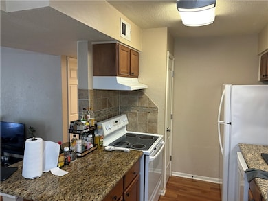 Kitchen featuring dark stone countertops, white ap