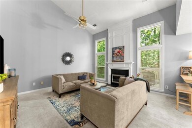 Living room featuring light colored carpet, healthy amount of natural light, ceiling fan, a large fireplace, and high vaulted ceiling