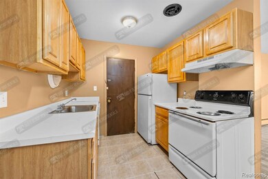 Kitchen featuring white appliances, light countertops, under cabinet range hood, and light tile patterned floors