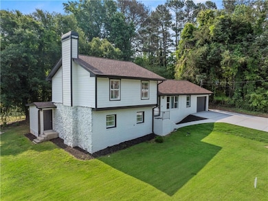 Tri-level home with driveway, a chimney, and a front yard