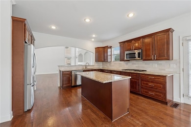 Kitchen featuring crown molding, stainless steel appliances, dark wood-style flooring, backsplash, and arched walkways
