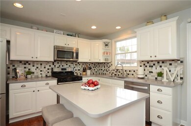 The kitchen offers bright white cabinetry, quartz 