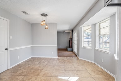 Unfurnished dining area with light tile patterned floors and a textured ceiling
