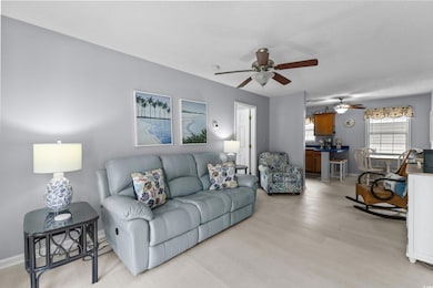 Living room featuring a ceiling fan, light wood-style floors, a textured ceiling, and baseboards