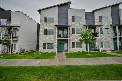 Contemporary home featuring a balcony, stone siding, and a front yard