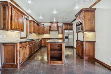 Kitchen featuring tasteful backsplash, a kitchen island, appliances with stainless steel finishes, ornamental molding, and open shelves
