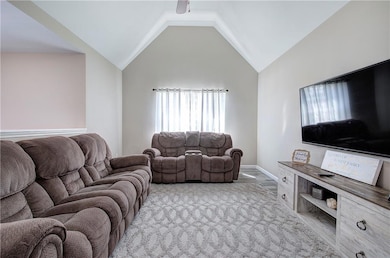 Living area with healthy amount of natural light, lofted ceiling, baseboards, and wood finished floors